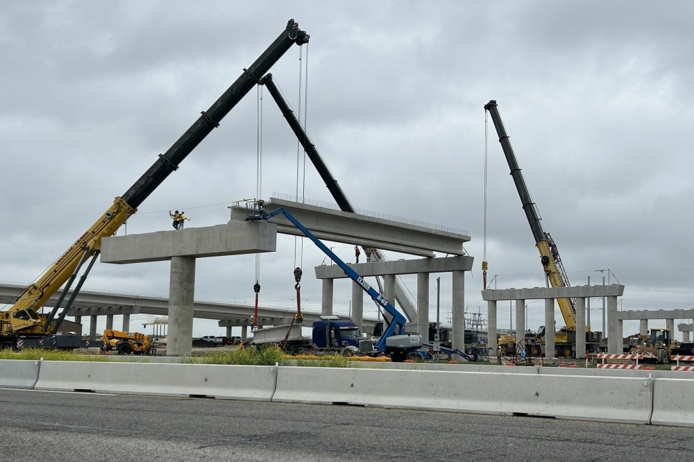 Cranes lifting concrete bridge sections at a construction site